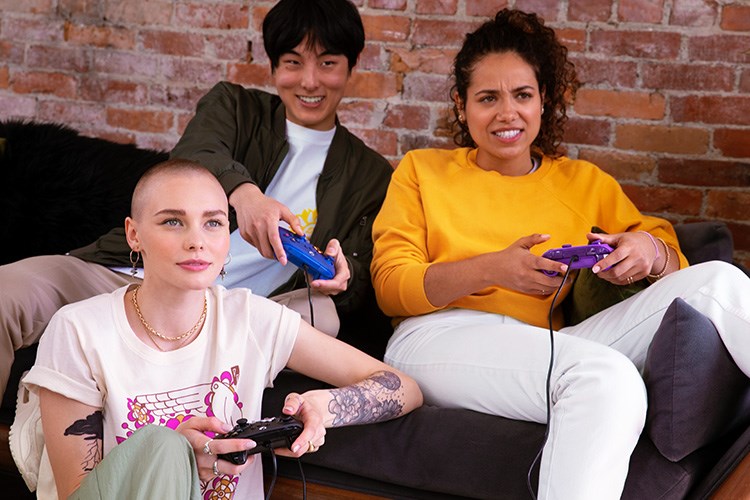 Friends playing videogames on the couch in a cozy livingroom